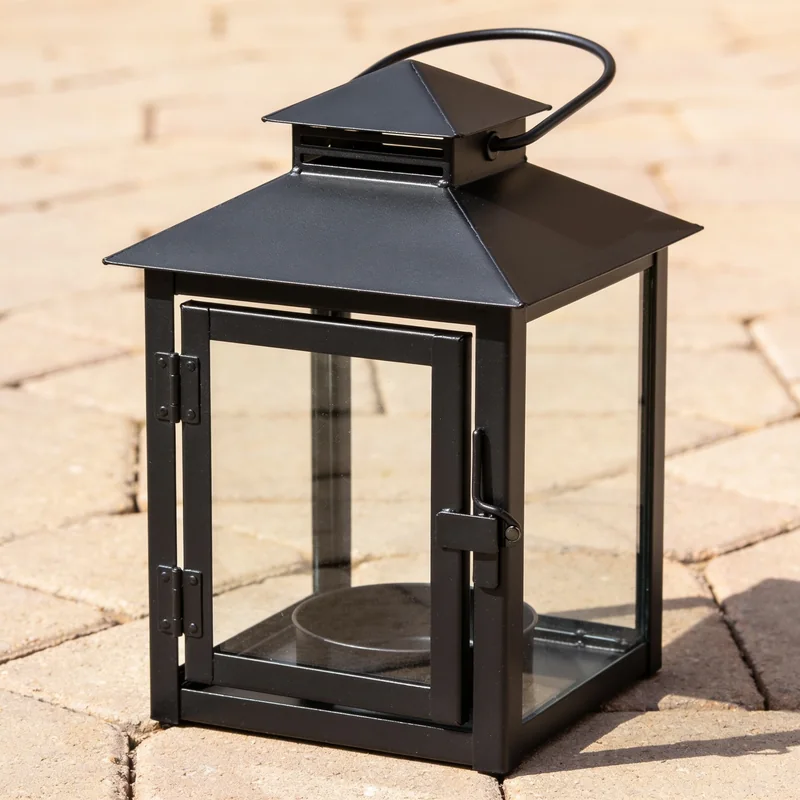 Empty black steel-and-glass candle lantern on pale paving